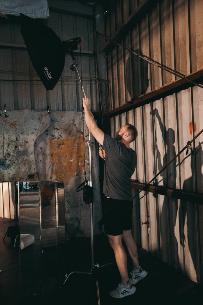 Un étudiant en photographie ajustant un projecteur de studio sur un plateau technique