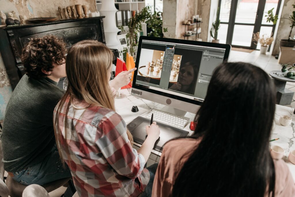 Trois professionnels retouchent et analysent des photographies dans Adobe Photoshop.